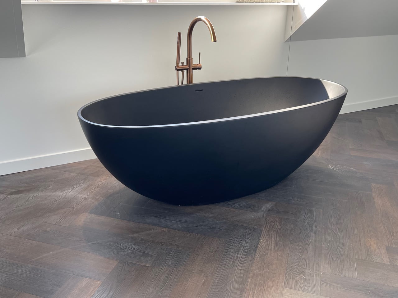 Matzwart vrijstaand bad met koperen kraan